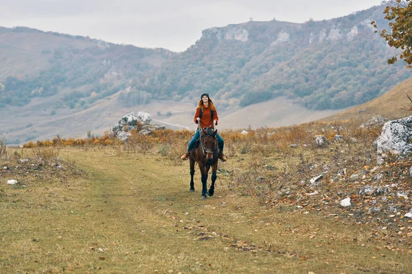 Mujer excursionista en las montañas montando un caballo aventura estilo de vida —  Fotos de Stock