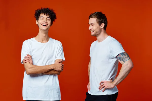 빨간 배경 우정의 흰색 티셔츠를 입은 두 남자가 웃고 있습니다. — 스톡 사진