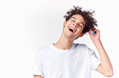 Kıvırcık saçlı, saçlarını tarayan, açık renk arka planı olan duygusal adam.