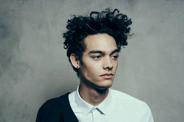 handsome guy with curly hair in a white shirt and jacket on a gray background photography studio portrait