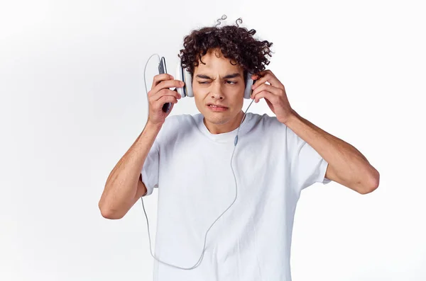 Camiseta adolescente y en auriculares sobre un fondo claro modelo de nueva tecnología —  Fotos de Stock