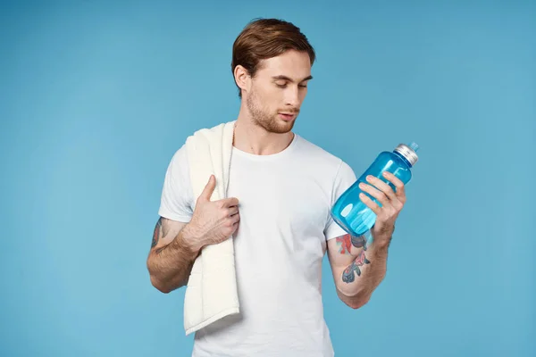 Спортсмен з татуюваннями на руках пляшка води енергія синій фон — стокове фото