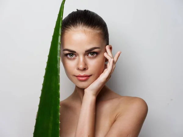 Retrato de uma mulher bonita com folha de aloés em um fundo leve ombros desnudados — Fotografia de Stock