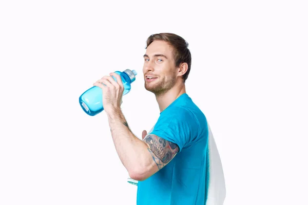 Sport uomo con tatuaggio sul suo braccio allenamento acqua bottiglia ritagliato vista luce sfondo — Foto Stock