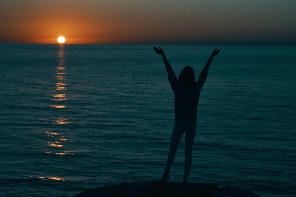 Sziluett egy férfi felemelt kézzel a parton és naplemente a háttérben — Stock Fotó