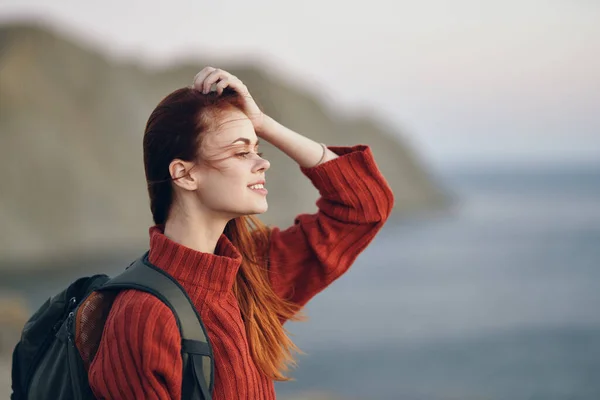 Bella donna in un maglione con uno zaino sulla schiena e mare montagne natura aria fresca — Foto Stock