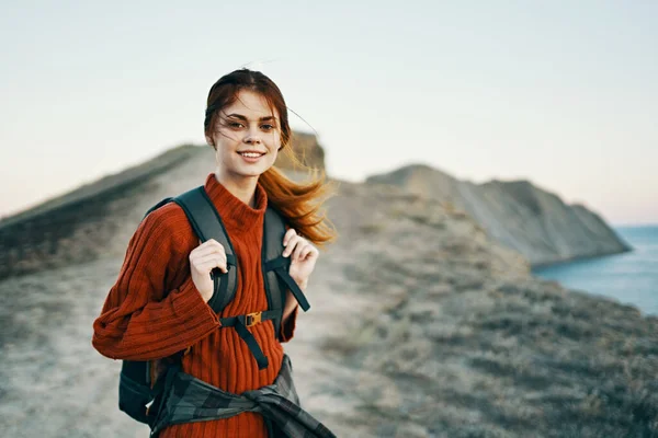 Ευτυχισμένη γυναίκα με σακίδιο στη φύση στα βουνά κοντά στη θάλασσα και το ηλιοβασίλεμα χαρούμενο μοντέλο χαμόγελο — Φωτογραφία Αρχείου