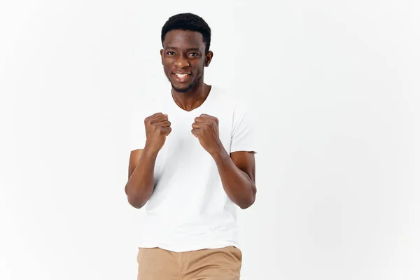 Hombre alegre en una camiseta blanca gestos con las manos emociones fondo claro — Foto de Stock