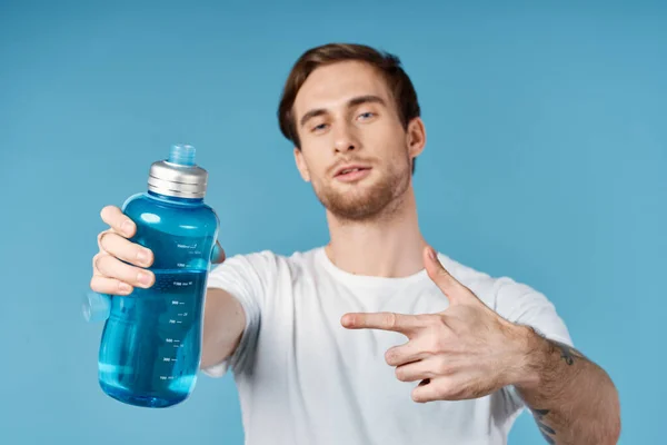 Uomo in bianco t-shirt bottiglia d'acqua dissetante vista ritagliata sfondo blu — Foto Stock