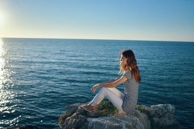 Gezgin, deniz kenarında, dağlarda ve günbatımında sahilde oturur.