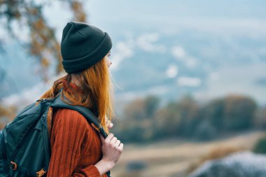Sırt çantalı bir kadın dağlarda seyahat ediyor.