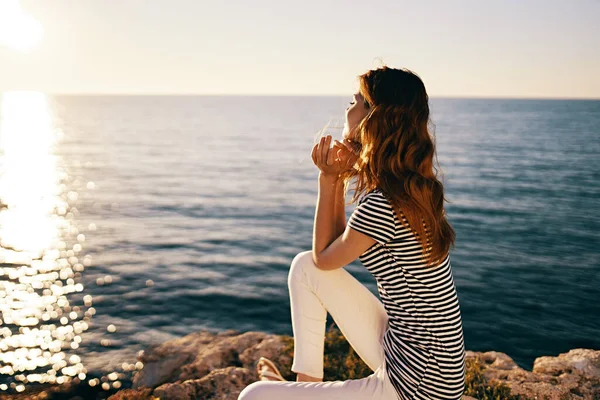 Denizin kıyısındaki sahilde oturan ve gün batımını izleyen bir kadın. — Stok fotoğraf