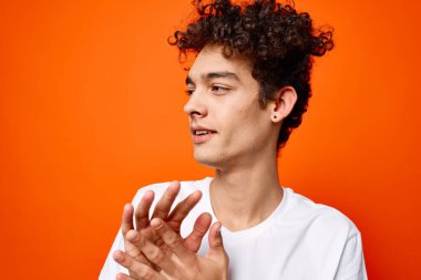 Beyaz tişörtlü adam elini turuncu arka planda gezdiriyor.