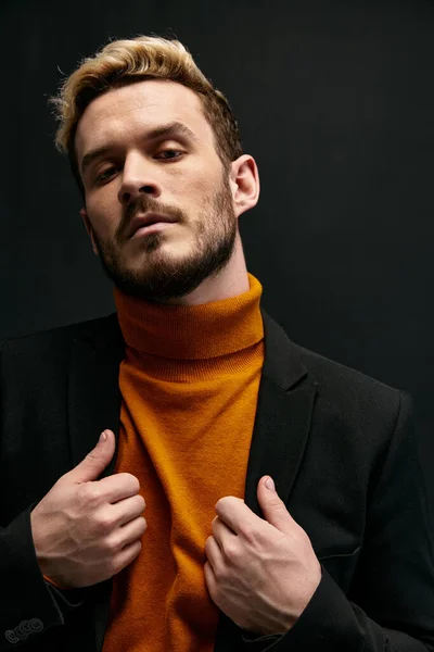 Homem em camisola laranja e casaco preto gesticulando com as mãos corte vista loira modelo — Fotografia de Stock