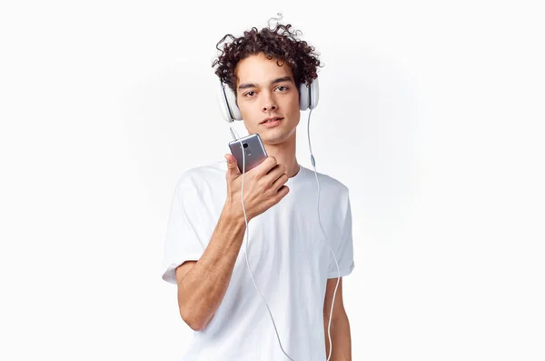 Кудрявый парень в наушниках с телефоном в руках музыкальная технология — стоковое фото