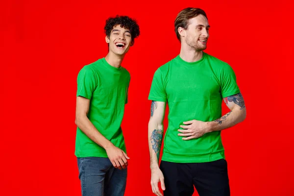 Due uomini in t-shirt verdi ridono gioia di comunicazione — Foto Stock