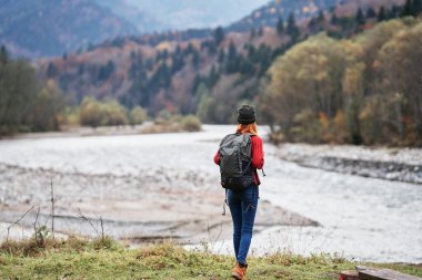 Sonbahar ormanlarında ve saydam nehir dağlarında doğa üzerine sırt çantasıyla gezen gezgin.