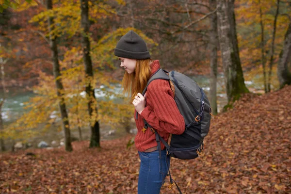 Frau mit Rucksack wandert im Herbstpark in Flussnähe in Naturseitensicht — Stockfoto