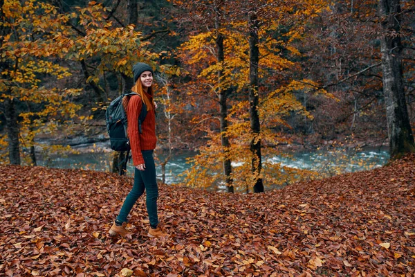 Um viajante com uma mochila caminha no parque na natureza perto do rio no outono — Fotografia de Stock