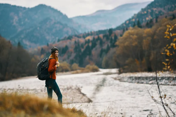 Mulher com mochila caminhadas pelo rio na paisagem montanhas — Fotografia de Stock