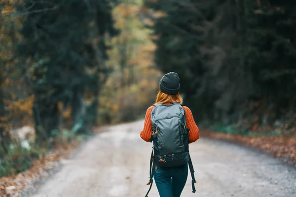 Viajante com uma mochila na floresta na estrada em árvores de outono modelo — Fotografia de Stock