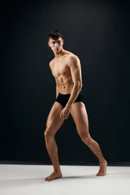 Siyah külotlu, kaslı, çıplak vücutlu, esmer bir adam.
