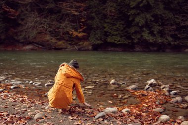 Nehir kıyısında yürüyen kadın, düşmüş doğa dağlarını terk ediyor.