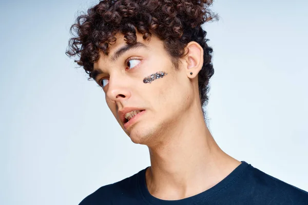 Curly-haired guy in a black t-shirt cosmetics on the face clean skin — Stock Photo, Image