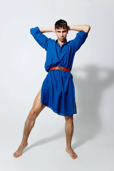 Knap gay man op een licht achtergrond in volledige groei blauw jurk — Stockfoto