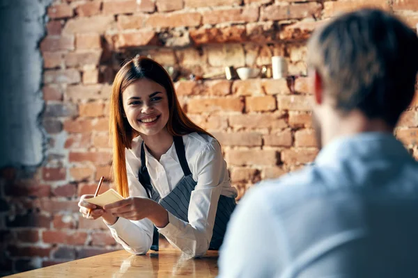 Una mujer recibe una orden de un hombre en un café que sirve a un camarero — Foto de Stock