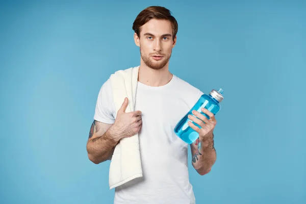 Uomo sportivo con tatuaggi sulle braccia bottiglia d'acqua energia sfondo blu — Foto Stock