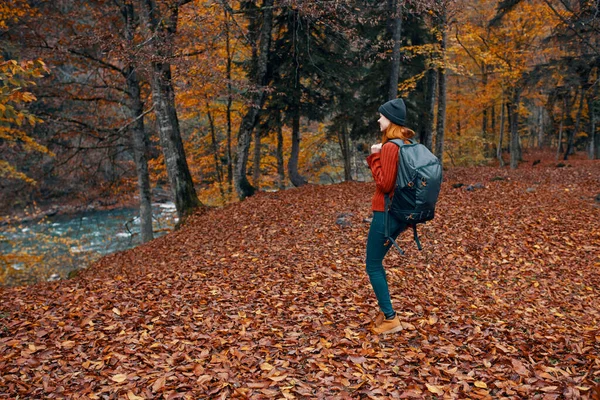 Donna in autunno nel parco con foglie cadute e uno zaino sul suo fiume posteriore sullo sfondo — Foto Stock