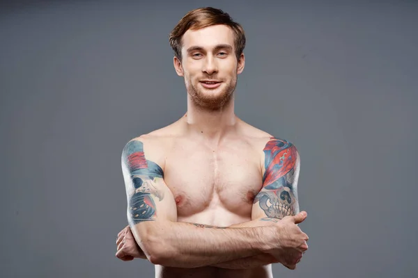 Сексуальный культурист с обнаженным туловищем из мышечных татуировок серый фон скрещенные руки на груди — стоковое фото
