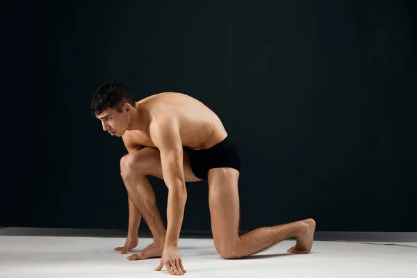 Спортивний чоловік мускулисте тіло чорні труси студії на колінах — стокове фото