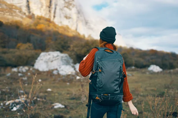 Een reiziger in een trui en een hoed rust in de bergen in de natuur en een rugzak op haar rug — Stockfoto