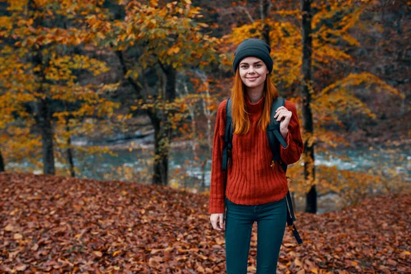 Осінній парк опале листя високих дерев річка на задньому плані і жінка подорожує туризмом — стокове фото