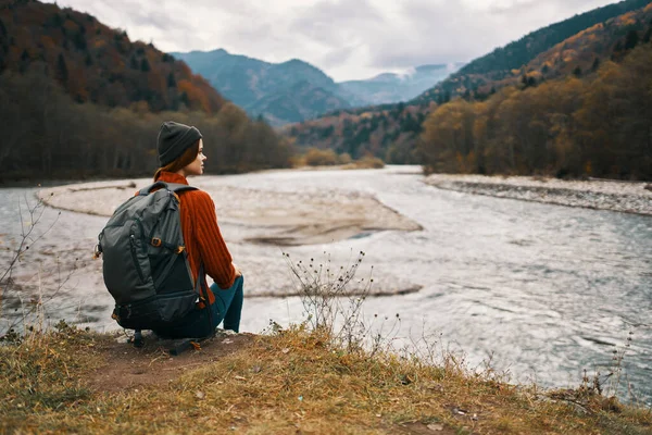 Путешественница в куртке с рюкзаком на спине шляпы горы пейзаж реки — стоковое фото