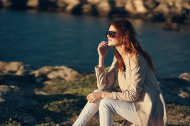 Yazın gün batımında güzel bir kadın deniz kenarında, dağların eteklerinde.