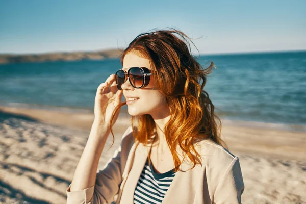 Atraktivní žena v slunečních brýlích na písku u moře v horách — Stock fotografie