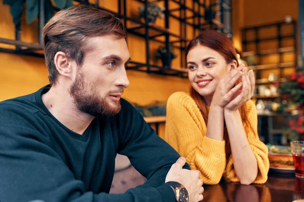 Homem e mulher estão sentados em um café na mesa e gesticulando com as mãos amigos emoções divertido interior — Fotografia de Stock