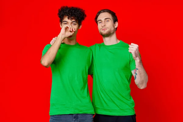 Divertenti amici verdi t-shirt abbracci emozioni gioia rosso sfondo — Foto Stock