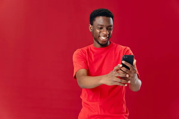 Africano americano em vermelho t-shirt corte vista telefone na mão — Fotografia de Stock