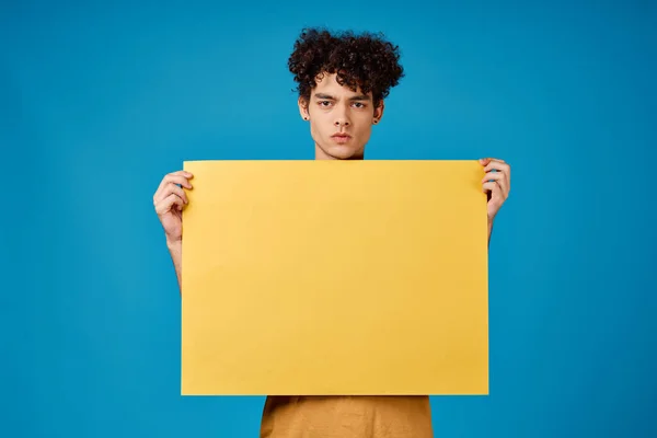 손에 노란 포스터를 든 남자, 카피 우주 광고푸른 배경을 가진 남자 — 스톡 사진