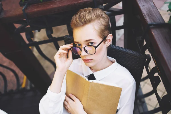 Vrouw aan tafel cafe ontwerp straat boek vrouw student dragen bril onderwijs — Stockfoto