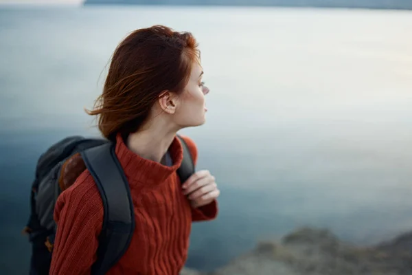 Жінка з рюкзаком в горах на відкритому повітрі біля моря повернула назад обрізану модель — стокове фото