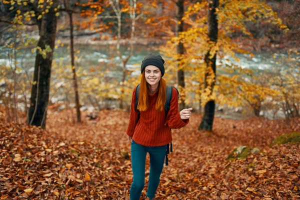 Mulher caminhante com mochila na floresta de outono perto do rio da montanha e folhas caídas — Fotografia de Stock