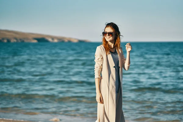 Woman in coat and striped t-shirt on the beach sea waves landscape mountains — Stock Photo, Image