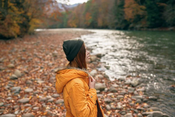 Vrouw in de herfst kleren op de natuur in de buurt van de rivier lopen de bergen — Stockfoto