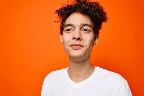 Lindo chico en blanco camiseta y diversión emociones primer plano naranja fondo — Foto de Stock