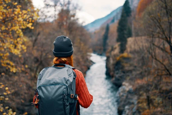 Mujer excursionista con una mochila en la espalda cerca de un río de montaña en la naturaleza, vista trasera —  Fotos de Stock